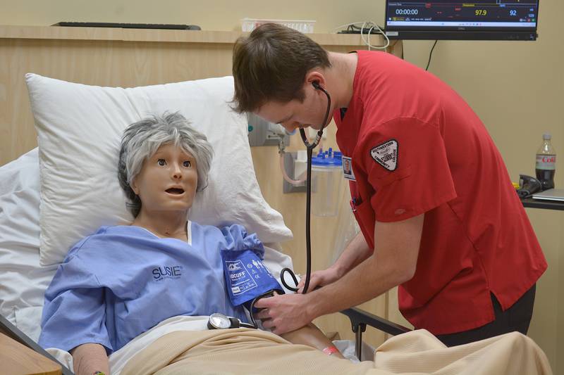 Gavin Evans checks a mannequin sim's blood pressure. The mannequin is able to have realistic body functions to give nursing students accessible experience.