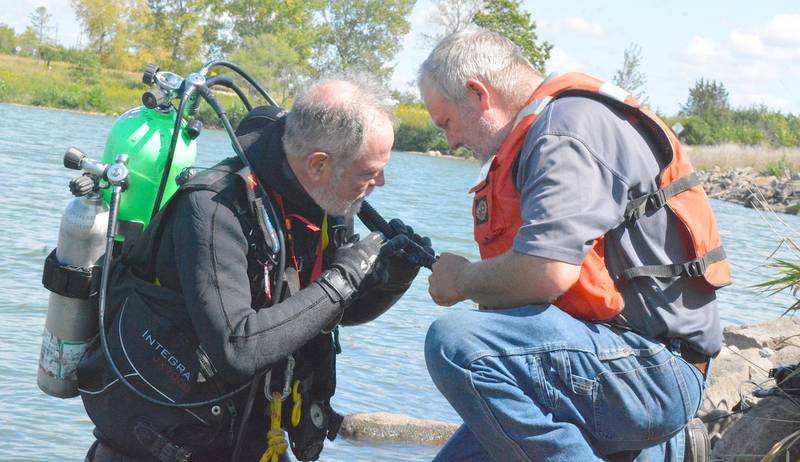 Two members of the dive team take a look at their equipment while preparing for a dive.