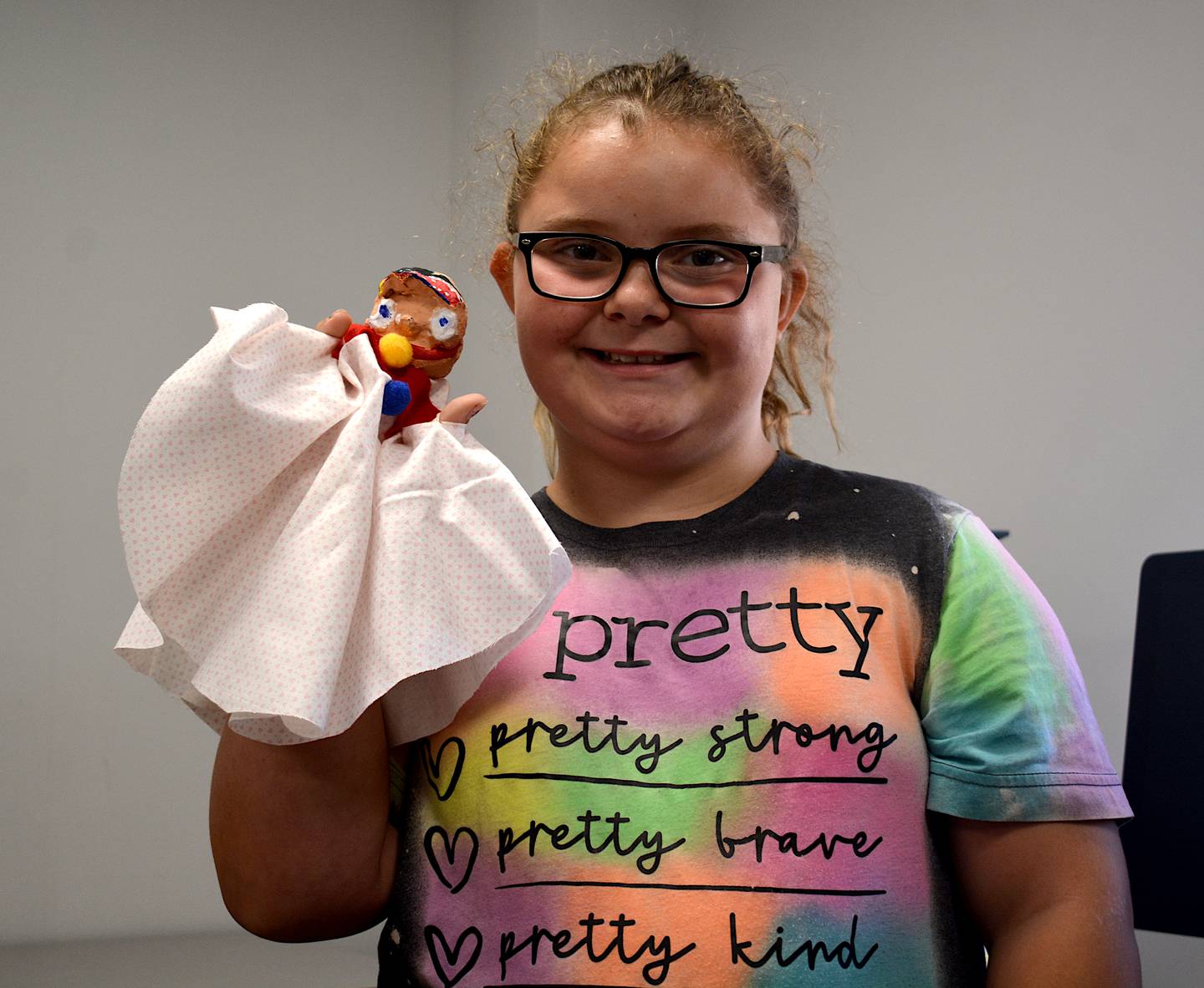 Madison Miller poses with her puppet, which she made herself. Choosing the fabric, painting the clay head and sewing cloth patches were done all by the morning workshop participants.