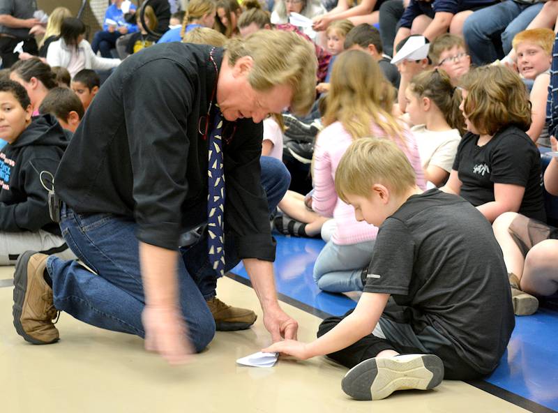 John Collins helps a student with his paper airplane, showing how to fold correctly. Collin, step-by-step, showed students how to fold the award-winning paper airplanes.