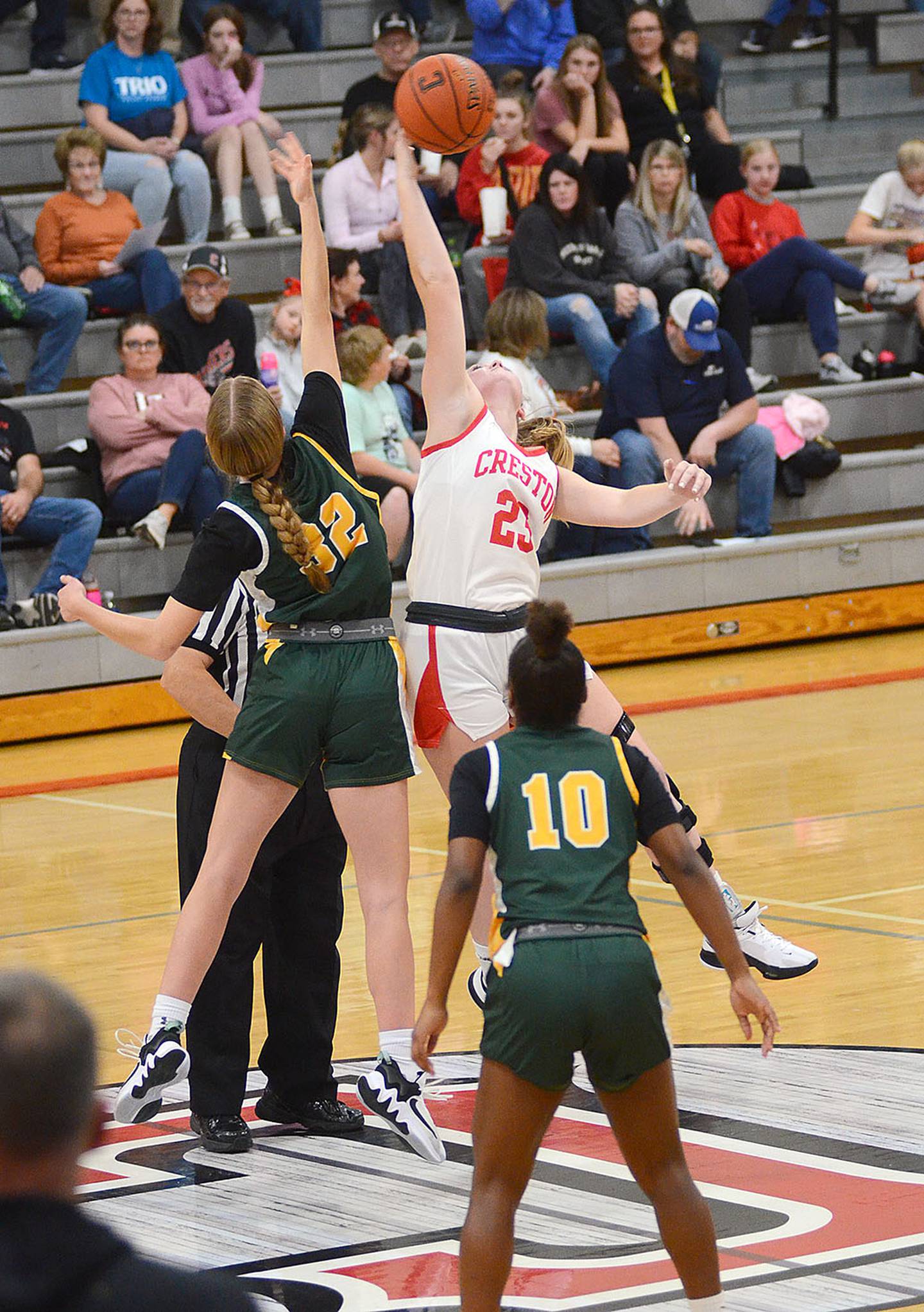 Creston 5-8 sophomore Brynn Tussey tips the ball to a teammate against Des Moines Hoover 5-10 center Eleanor Ekwall to tip off the 2023-24 season Friday night. Tussey had 11 ponts and five rebounds in the 53-10 victory.