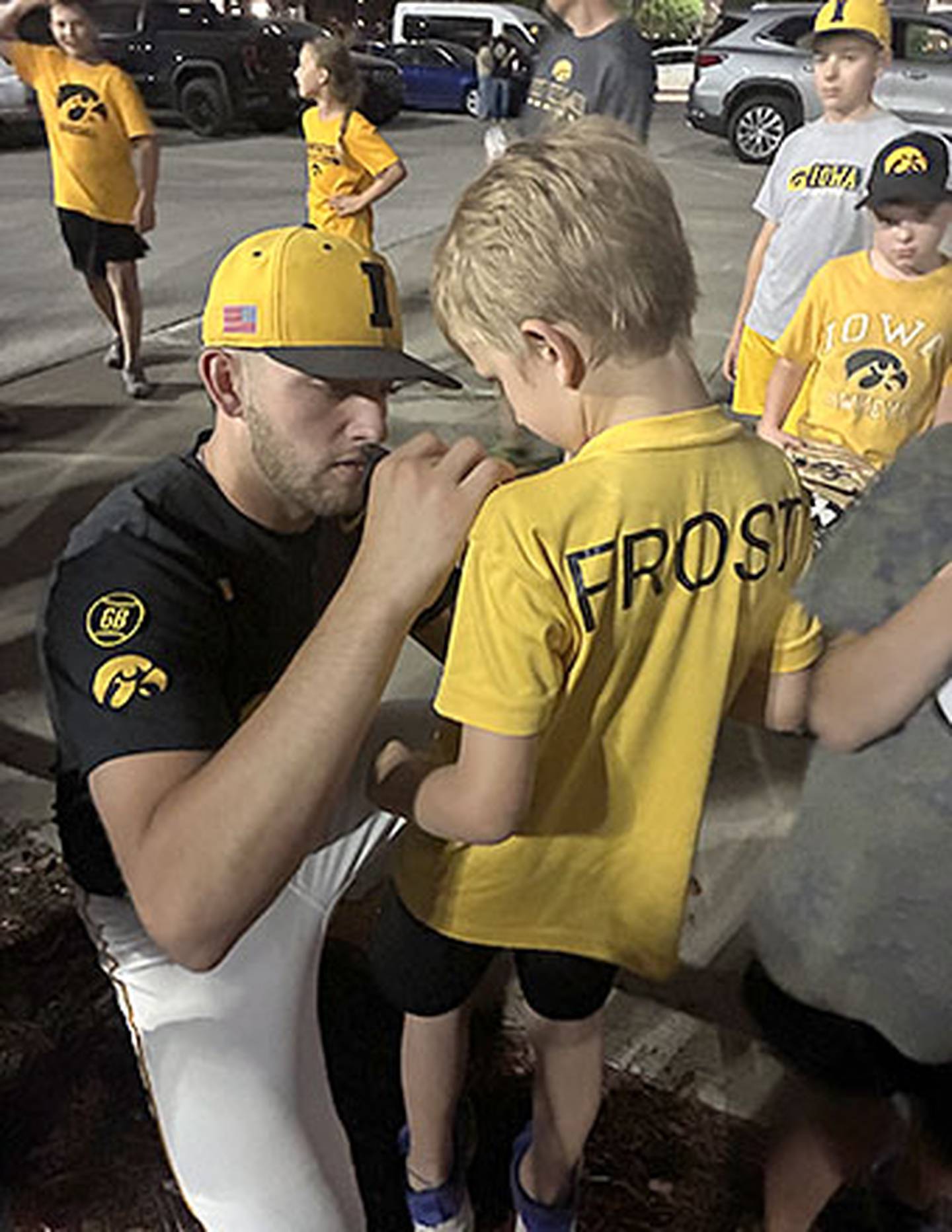 Jaixen Frost of the University of Iowa baseball team signs a young fan's shirt outside Principal Park after Friday's game.