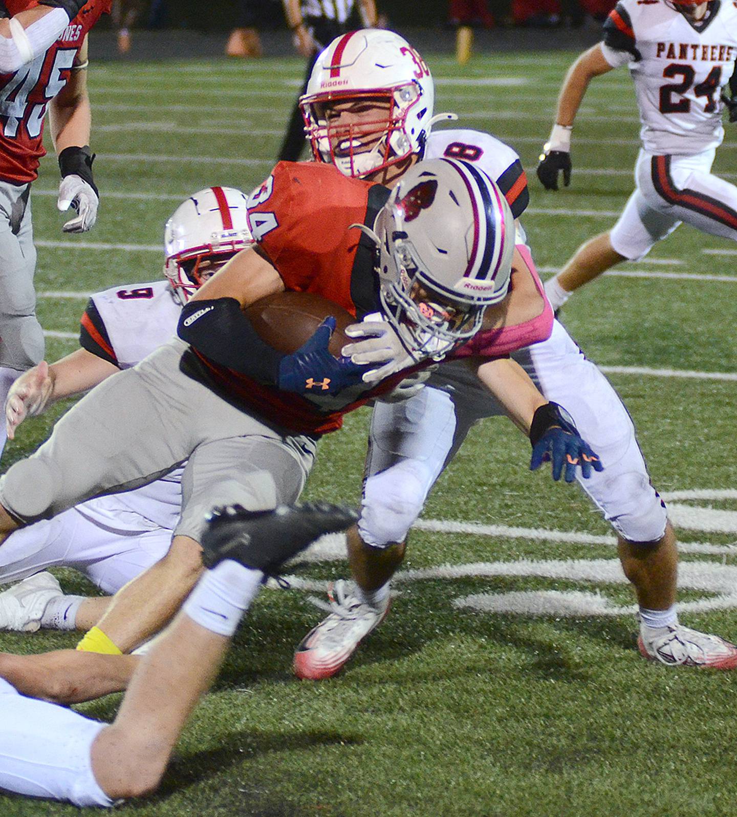 Creston safety Lane Travis (34) wraps up Harlan running back Ayden Redmon (34) with help from Brodrick Phelps (9).