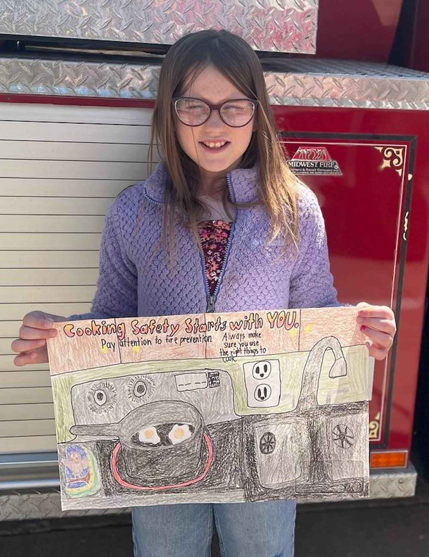 Fourth-grader Mary Keller and her contest-winning poster. The theme this year was based on cooking safety.