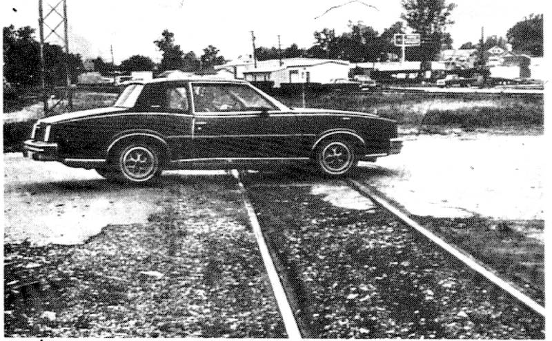 People driving over the Elm Street crossing these days are doing it while driving slowly and with caution. The crossing surface is in need of repair. This car is driving around a huge deteriorated section in the northbound lane.