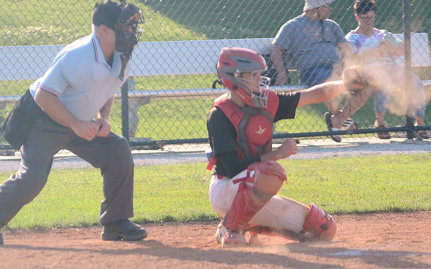 Dust flies from Brady McDonald's catcher's mitt after receiving a pitch from Tom Mikkelsen during the first game of Wednesday's doubleheader.