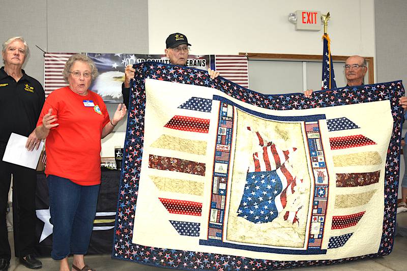 Duane Avey (middle) receives a quilt from the Red, White and Blue Quilt Guild at the Veterans Resource Fair held Thursday, Sept. 14, presented by Grace Evans. The quilt guild will be doing a presentation in November, however Avey won't be available for that presentation.