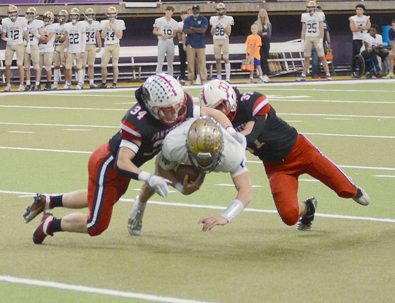 Creston's Milo Staver (34) and Lucas Travis (37) stop Bishop Heelan quarterback Quinn Olson for a loss during Saturday's semifinal game.