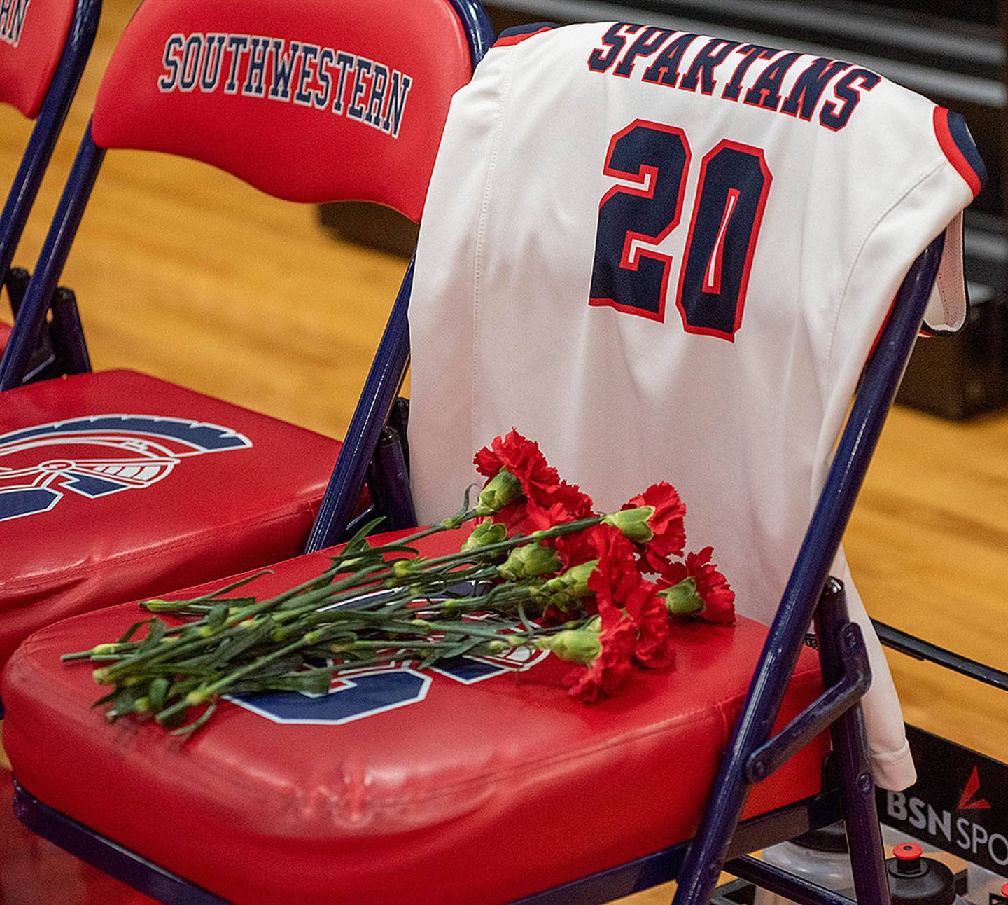 Flowers adorn the bench seat left empty in Maddie Stewart's honor before Monday's home game.