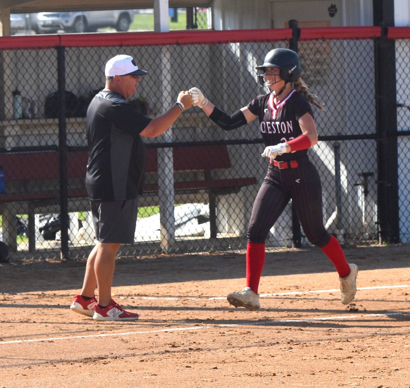 Avery Staver fist bumps coach Dave Hartman as she comes into home for her first home run of the night.