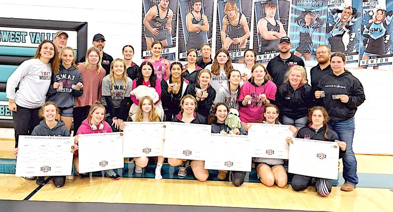 Wrestlers and coaches for the SWAT Valkyries girls wrestling team celebrate winning the Pride of Iowa Conference Tournament in Corning.