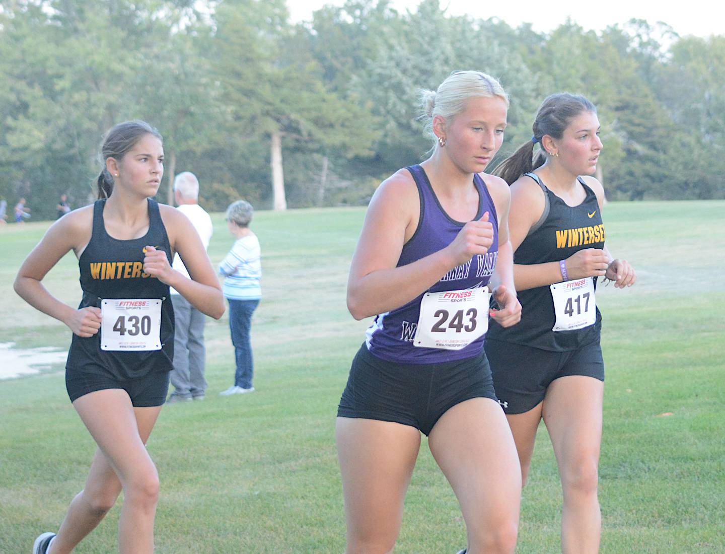 Wolverine senior Annika Nelson runs with a couple of competitors from Winterset in the Huskies' home cross country meet recently.