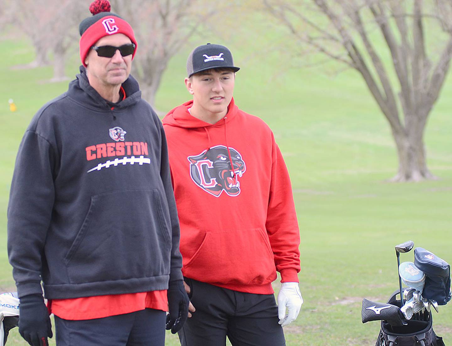 Creston golfer Ethan Holliday confers with coach Steve Shantz in lining up his approach shot to the No. 3 green in Thursday's dual meet against Atlantic.