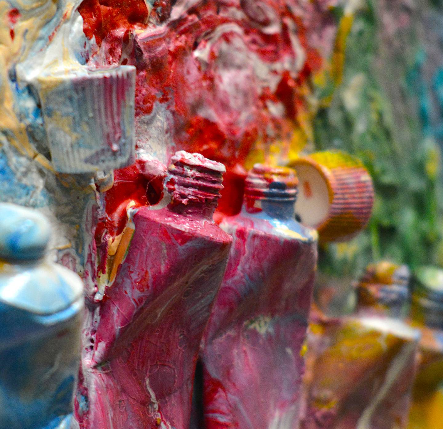Empty paint tubes are painted over and repurposed in one piece. The effect creates a three-dimensional element to each art piece.