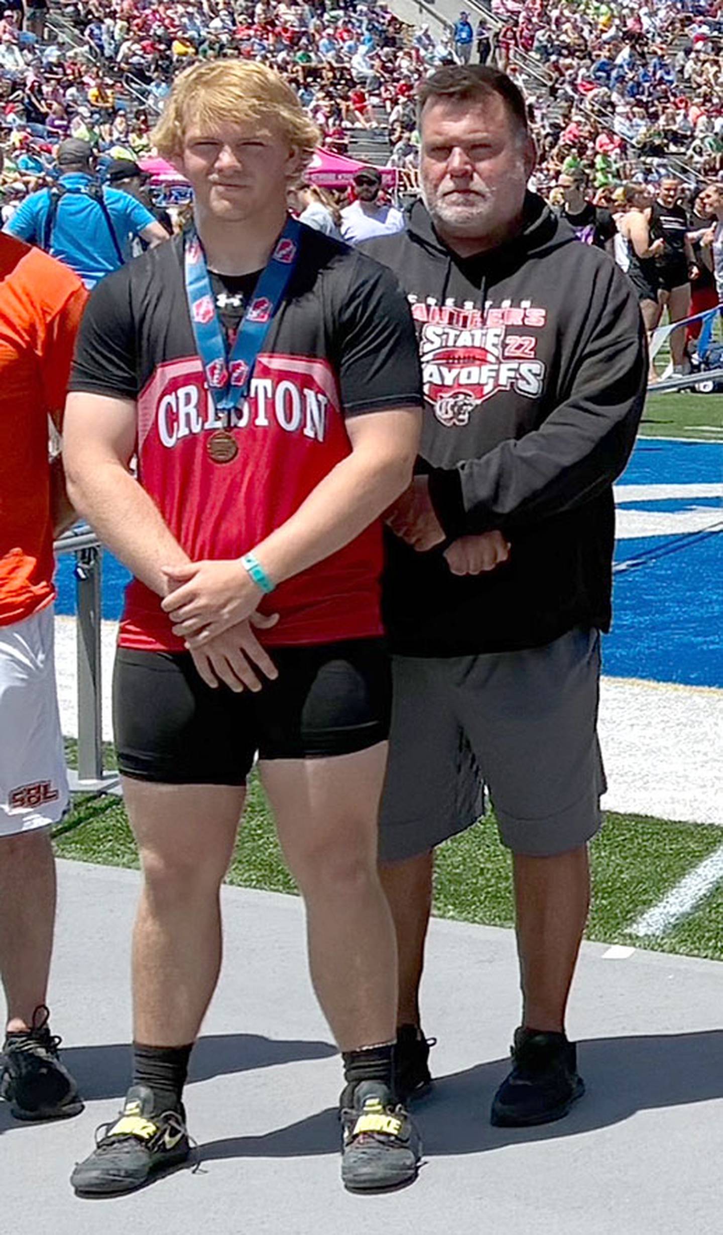 Creston sophomore Tom Mikkelsen is shown with throwing coach Brian Morrison after he was presented the seventh-place medal in the Class 3A shot put with a throw of 53-2.75.