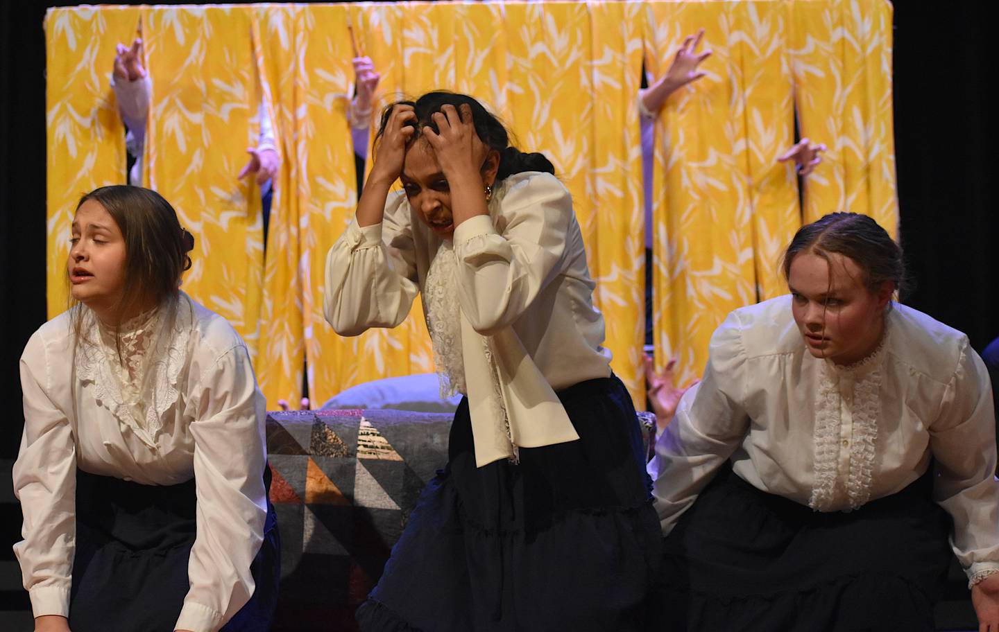 Hands burst through the titular yellow wallpaper during a performance from Creston's choral reading team.