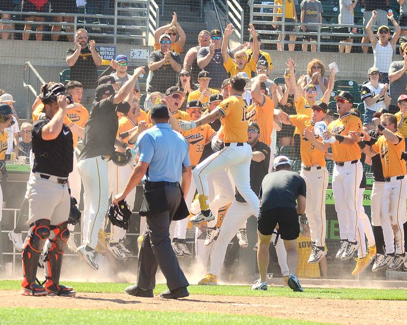 Iowa's Jaixen Frost of Mount Ayr (12) leaps into a throng of teammates celebrating his game-tying home run in the 10th inning Sunday against Oregon State at Principal Park.