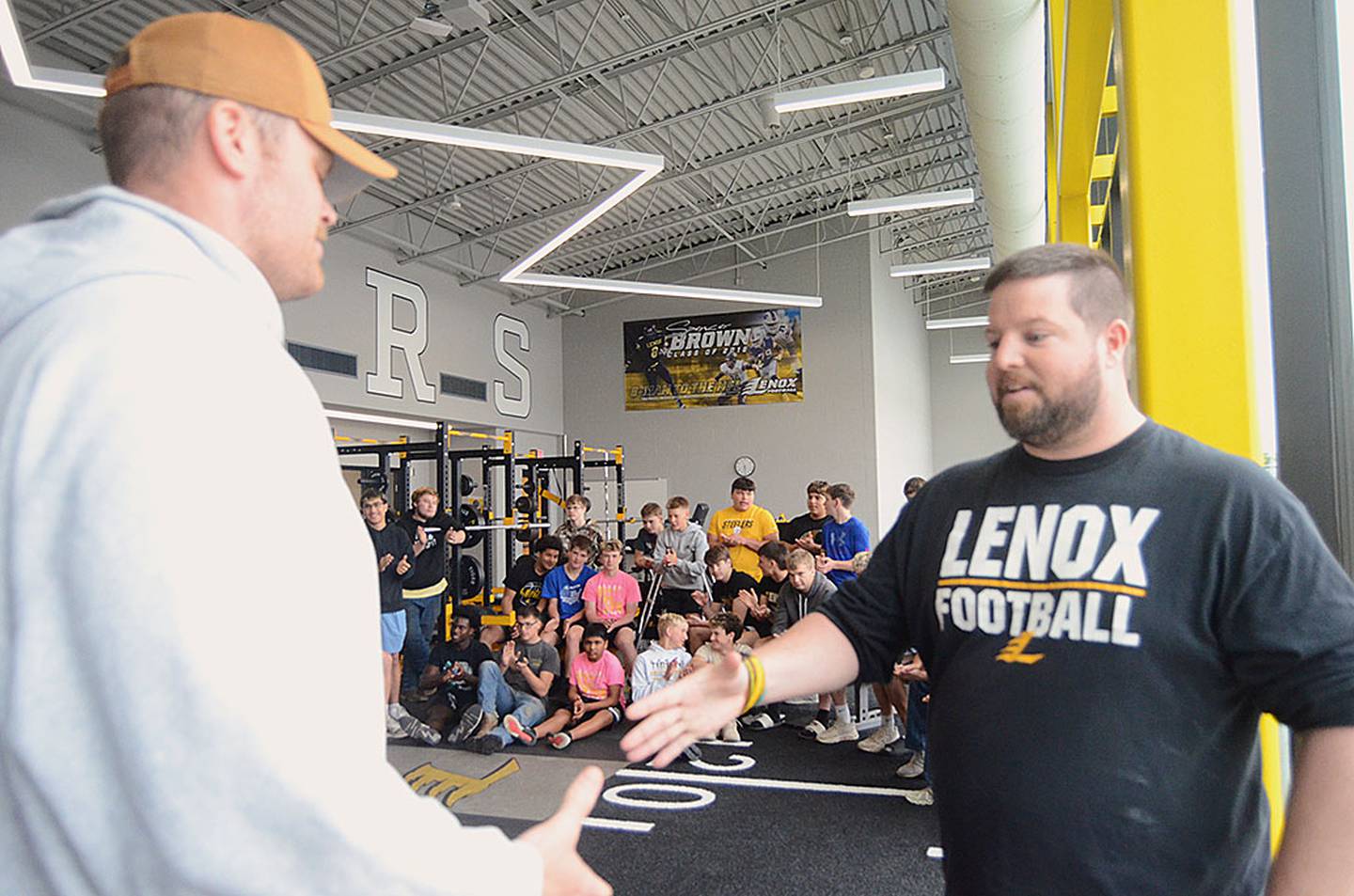 Lenox co-coach Michael Nardini greets 2016 graduate Spencer Brown in the team's weight room as he announced Brown's No. 8 uniform number will be retired.