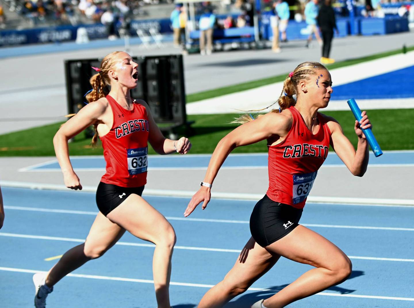 Cora Smith takes a handoff from leadoff runner Avery Staver Saturday morning at the Drake Relays.