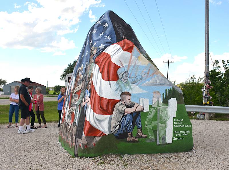 This portion of the Freedom Rock, which faces south, pays homage to veterans battling post traumatic stress disorder (PTSD) and shows a veteran sitting in a cemetery and staring at the grave of his brother-in-arms, as he remembers the chaos of battle.