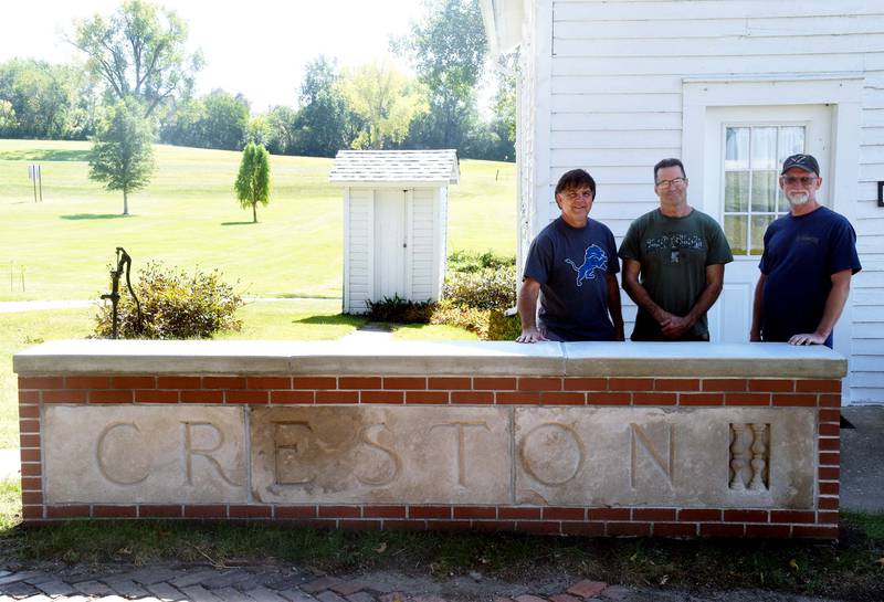 John Walters, Mike Seddon and Dan Adamson stand behind the restored Creston sign from the old high school. The limestone sign is located at the schoolhouse in the Creston Historical Village in McKinley Park.