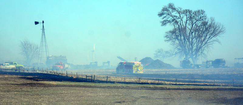 Hazy smoke-filled conditions loom over a farmstead as fire crews from Orient and other communities try to protect it during a massive six-alarm field fire Friday afternoon.
