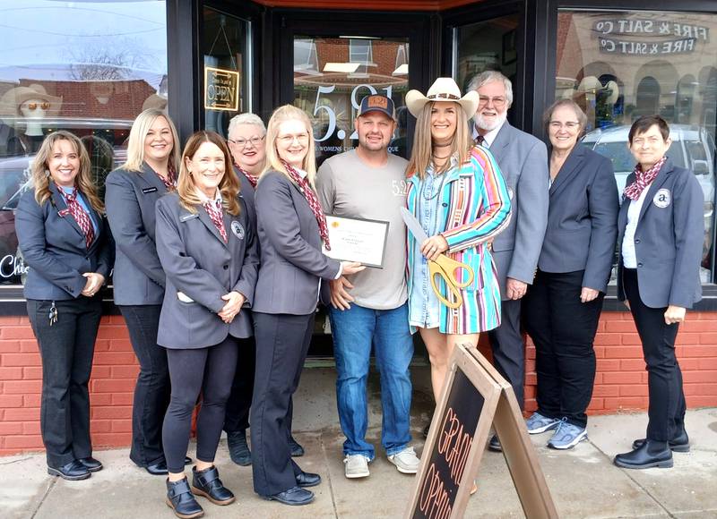 Owner Wendy Edwards smiles with her husband Nick and the Adams Community Chamber of Commerce at the grand opening of her new store.