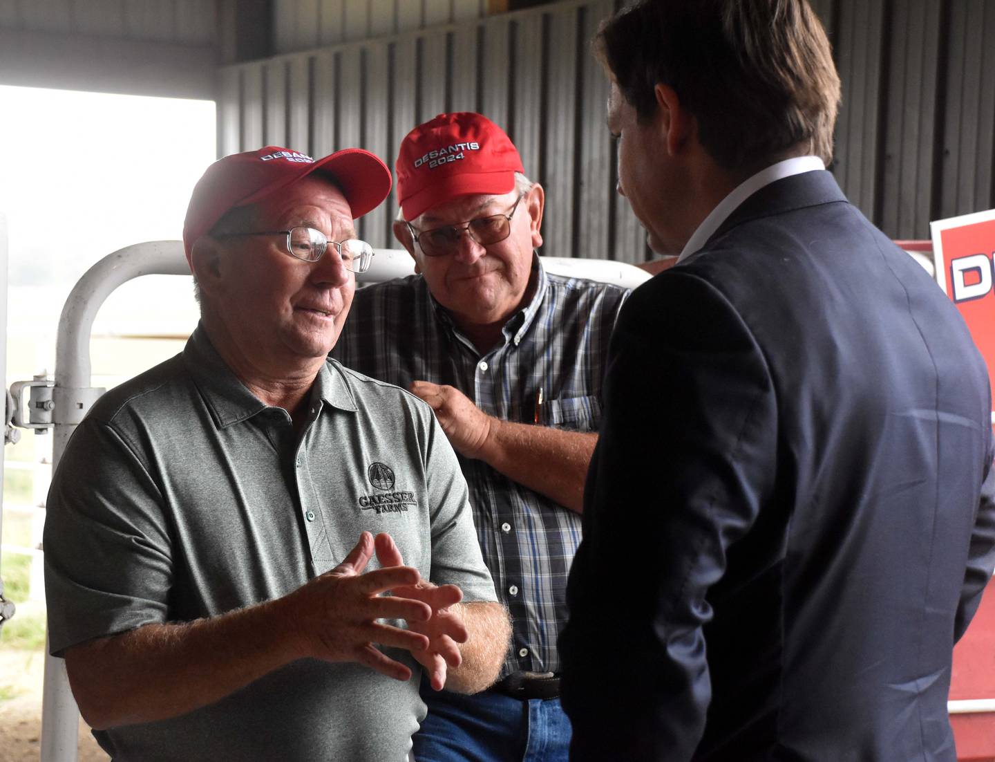 Roy Gaesser of Adams County, left, shares his farming legislative priorities with Gov. DeSantis, right. Behind is Iowa state representative Tom Shipley.