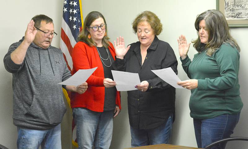 Jeff Burger (left), Michelle Burger (second from right) and Kristie Nixon (right) are sworn in to their positions as council members and mayor. City Clerk Kayla Lacina (second from left) assists.