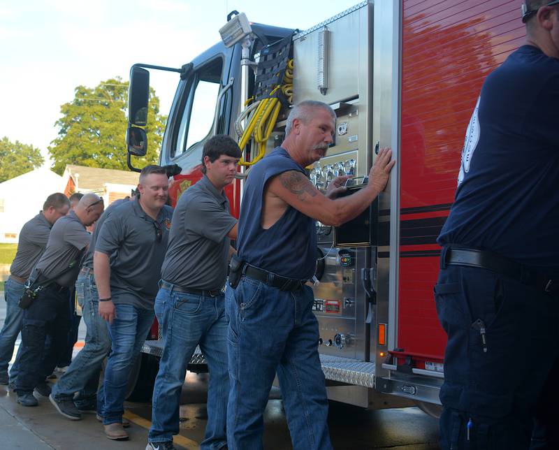 Members of the Creston Fire Department, alongside EMS and other surrounding Union County fire departments help push the new tanker into the station house for the first time during Thursday's push-in ceremony.
