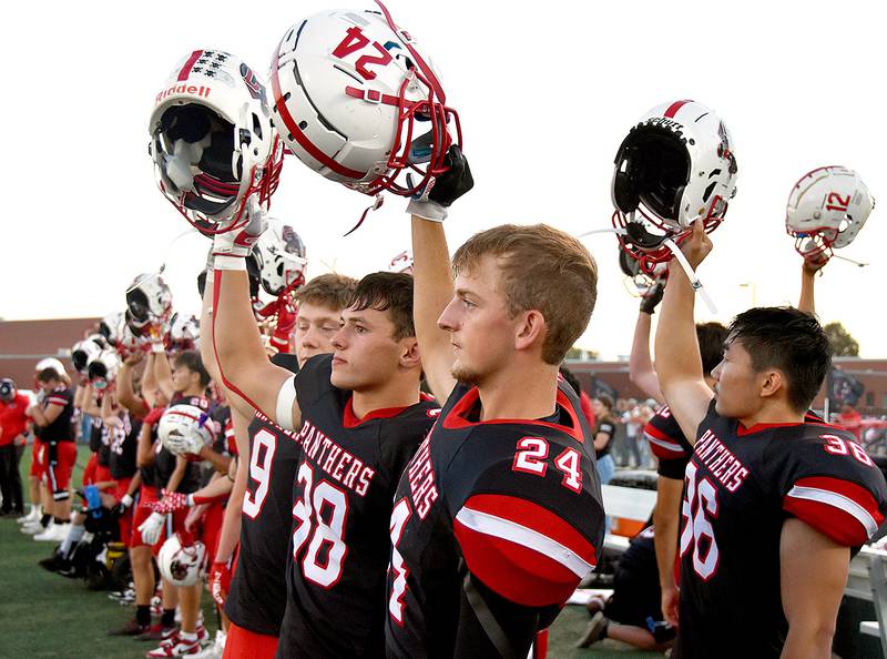 Creston football players raise their helmets prior to the opening kickoff at last week's homecoming game against Atlantic. Among them are, from left, Brodrick Phelps (9), Lane Travis (38), Davin Wallace (24) and Kobe Choung (36). Kickoff this week is 7 p.m. at Merrill Field in Harlan.