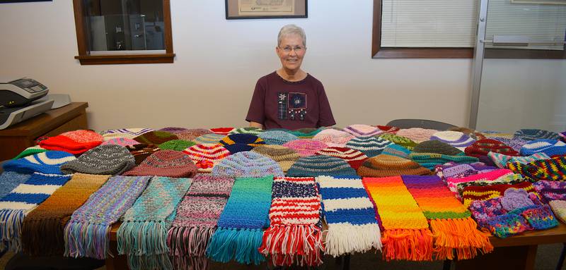 Nancy Parker with only a portion of the hats and scarves she crocheted for the Kiwanis Keep a Kid Warm Coat Giveaway. About half of the items made for the fundraiser are pictured.